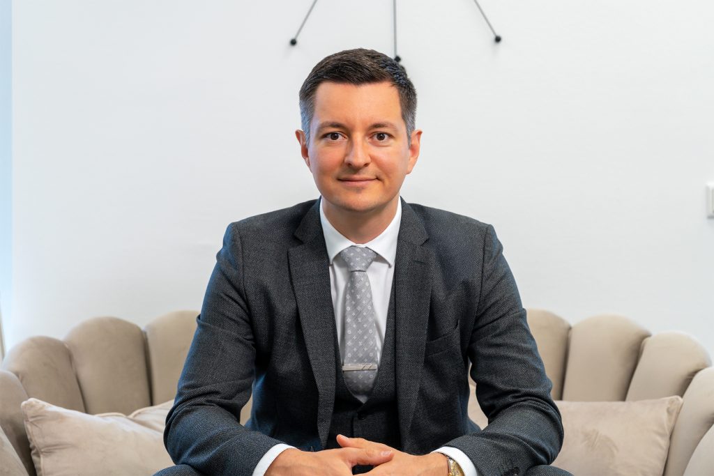David Deindl, Gesch&auml;ftsf&uuml;hrer und Immobilienberater bei David Deindl Immobilien, l&auml;chelnd auf Couch